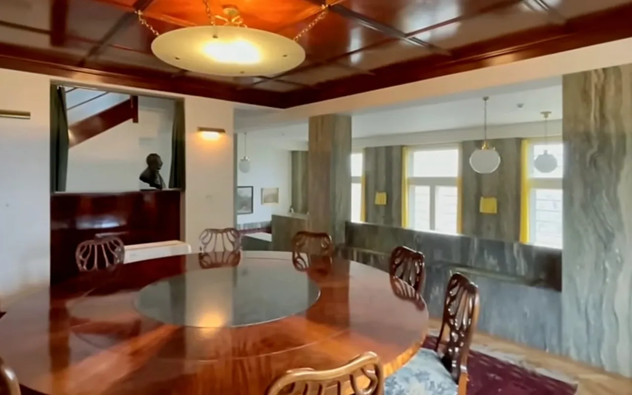 The dining room of Villa Müller with a round mahogany table and a coffered wooden ceiling
