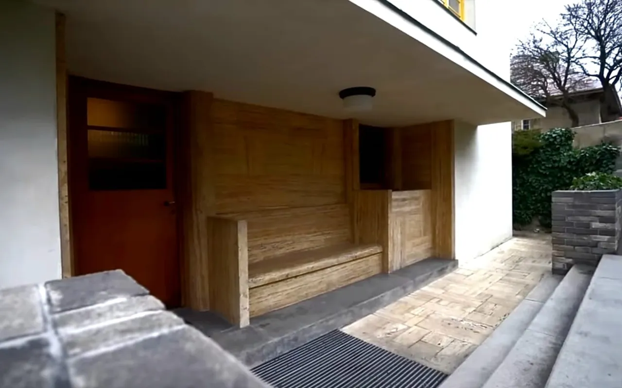 The entrance niche of Villa Müller: a wooden bench and door set into the white wall below street level